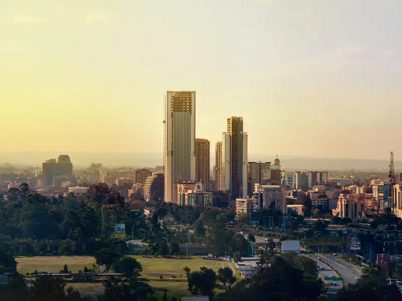 The Nairobi skyline at sunset, the high-rise district and Britam Tower standing above the treeline.