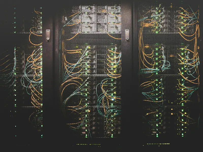 A server cabinet seen head on, densely patched with fibre and dotted with status lights.