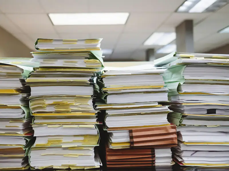 Stacks of tabbed and bound working papers on a desk in an office.